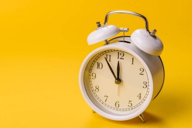 Ofis ve iş yerlerindeki son teslim tarihleri için kavramsal bir arkaplan olarak sarı yüzeyde klasik alarm saati