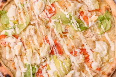 Peynirli ve tavuklu İtalyan sezar pizzası, marul yaprağı ve sos. Fast food, dilimlenmiş pizza.