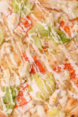 Peynirli ve tavuklu İtalyan sezar pizzası, marul yaprağı ve sos. Fast food, dilimlenmiş pizza.