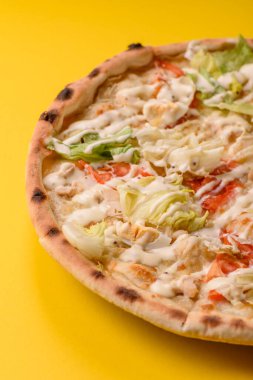 Peynirli ve tavuklu İtalyan sezar pizzası, marul yaprağı ve sos. Fast food, dilimlenmiş pizza.