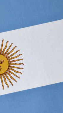 Arjantin bayrağı arka plan olarak sarı ve mavi renkte. Arjantin Ulusal Bayrağı