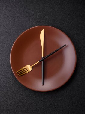 Boş tabak ve saat şeklinde cihazlar öğle yemeği molası, kahve molası, yemek molası için kavramsal bir arka plan olarak kullanılıyor.