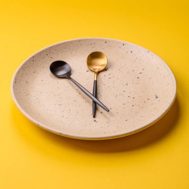 Boş tabak ve saat şeklinde cihazlar öğle yemeği molası, kahve molası, yemek molası için kavramsal bir arka plan olarak kullanılıyor.