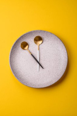 Boş tabak ve saat şeklinde cihazlar öğle yemeği molası, kahve molası, yemek molası için kavramsal bir arka plan olarak kullanılıyor.