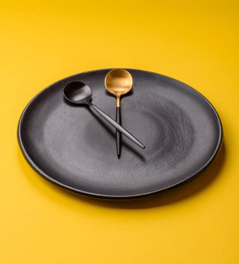 Boş tabak ve saat şeklinde cihazlar öğle yemeği molası, kahve molası, yemek molası için kavramsal bir arka plan olarak kullanılıyor.