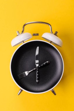 Boş tabak ve saat şeklinde cihazlar öğle yemeği molası, kahve molası, yemek molası için kavramsal bir arka plan olarak kullanılıyor.