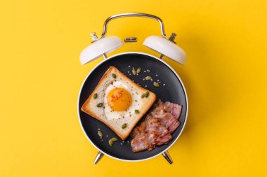 Pastırmalı, sosisli ve sebzeli sahanda yumurta. Kaliteli bir çalar saatin üzerindeki tabak şeklinde kahvaltı.