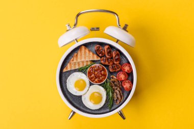 Pastırmalı, sosisli ve sebzeli sahanda yumurta. Kaliteli bir çalar saatin üzerindeki tabak şeklinde kahvaltı.