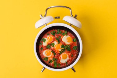 Pastırmalı, sosisli ve sebzeli sahanda yumurta. Kaliteli bir çalar saatin üzerindeki tabak şeklinde kahvaltı.