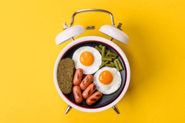 Pastırmalı, sosisli ve sebzeli sahanda yumurta. Kaliteli bir çalar saatin üzerindeki tabak şeklinde kahvaltı.