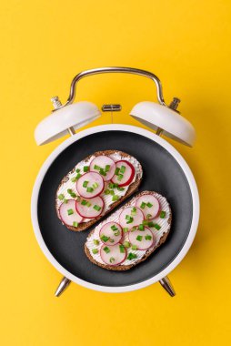 Tost, ton balığı ve avokado ile kahvaltı sandviçi. Kaliteli çalar saatin kadranı yerine tabak konsepti olarak kahvaltı.