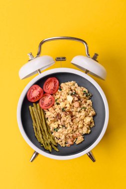 Pastırmalı, sosisli ve sebzeli sahanda yumurta. Kaliteli bir çalar saatin üzerindeki tabak şeklinde kahvaltı.