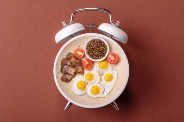 Pastırmalı, sosisli ve sebzeli sahanda yumurta. Kaliteli bir çalar saatin üzerindeki tabak şeklinde kahvaltı.