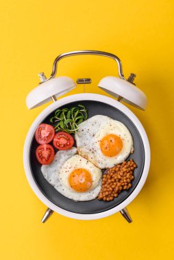 Pastırmalı, sosisli ve sebzeli sahanda yumurta. Kaliteli bir çalar saatin üzerindeki tabak şeklinde kahvaltı.