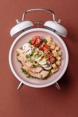 Tavuklu Sezar salatası, kızarmış ekmek, domates ve tohumlu yumurta. Kaliteli çalar saatin kadranı yerine tabak konsepti olarak kahvaltı.