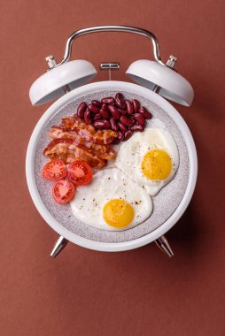 Pastırmalı, sosisli ve sebzeli sahanda yumurta. Kaliteli bir çalar saatin üzerindeki tabak şeklinde kahvaltı.