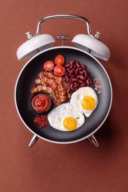 Pastırmalı, sosisli ve sebzeli sahanda yumurta. Kaliteli bir çalar saatin üzerindeki tabak şeklinde kahvaltı.