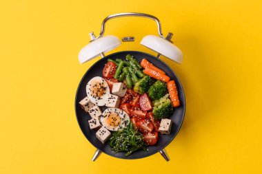 Tavuklu Sezar salatası, kızarmış ekmek, domates ve tohumlu yumurta. Kaliteli çalar saatin kadranı yerine tabak konsepti olarak kahvaltı.