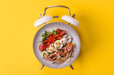 Tavuklu Sezar salatası, kızarmış ekmek, domates ve tohumlu yumurta. Kaliteli çalar saatin kadranı yerine tabak konsepti olarak kahvaltı.