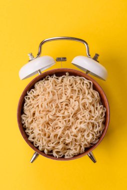 Çalar saatin arka planında et, sos ve sebzeli İtalyan makarnası. Makarna yemek için kavramsal arka plan zamanı