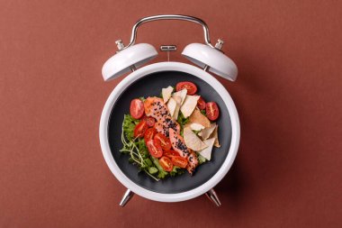 Tavuklu Sezar salatası, kızarmış ekmek, domates ve tohumlu yumurta. Kaliteli çalar saatin kadranı yerine tabak konsepti olarak kahvaltı.