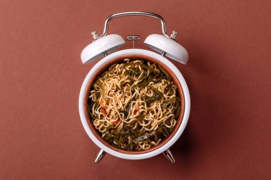 Çalar saatin arka planında et, sos ve sebzeli İtalyan makarnası. Makarna yemek için kavramsal arka plan zamanı