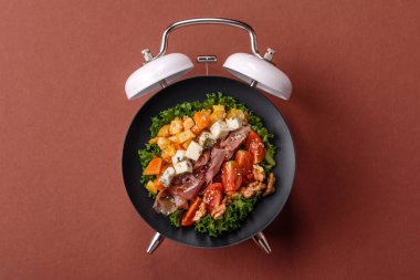 Tavuklu Sezar salatası, kızarmış ekmek, domates ve tohumlu yumurta. Kaliteli çalar saatin kadranı yerine tabak konsepti olarak kahvaltı.