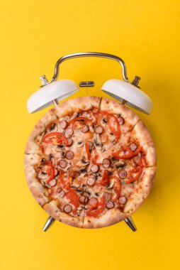 Dilimlenmiş İtalyan pizzası yeme ve restorandan teslim etme zamanı. Klasik bir çalar saatin tuşundaki pizza şeklindeki kavram.