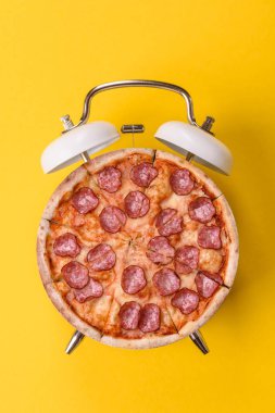 Dilimlenmiş İtalyan pizzası yeme ve restorandan teslim etme zamanı. Klasik bir çalar saatin tuşundaki pizza şeklindeki kavram.