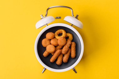Peynir çubukları, kızarmış mozzarella, soslu fast food. Çalar saat skorbordunda tabakla fast food yeme zamanı.