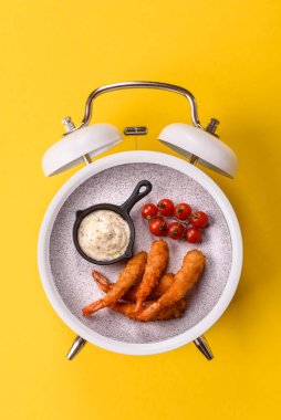 Ekmekli ya da tempuralı karides, abur cubur, paket yiyecek. Fast food 'u klasik bir çalar saat skorbordunda tabak ile yeme zamanı.