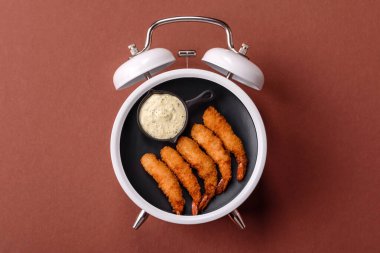 Ekmekli ya da tempuralı karides, abur cubur, paket yiyecek. Fast food 'u klasik bir çalar saat skorbordunda tabak ile yeme zamanı.