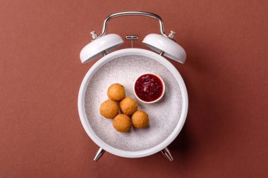 Peynirli toplar, kızarmış mozzarella kroketleri, soslu ekmek arası fast food. Çalar saat skorbordunda tabakla fast food yeme zamanı.