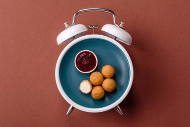 Peynirli toplar, kızarmış mozzarella kroketleri, soslu ekmek arası fast food. Çalar saat skorbordunda tabakla fast food yeme zamanı.