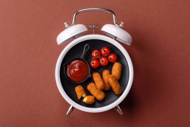 Peynir çubukları, kızarmış mozzarella, soslu fast food. Çalar saat skorbordunda tabakla fast food yeme zamanı.