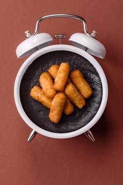 Peynir çubukları, kızarmış mozzarella, soslu fast food. Çalar saat skorbordunda tabakla fast food yeme zamanı.