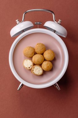 Peynirli toplar, kızarmış mozzarella kroketleri, soslu ekmek arası fast food. Çalar saat skorbordunda tabakla fast food yeme zamanı.