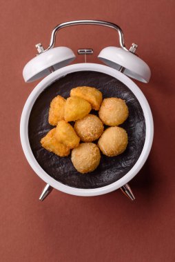 Peynirli toplar, kızarmış mozzarella kroketleri, soslu ekmek arası fast food. Çalar saat skorbordunda tabakla fast food yeme zamanı.