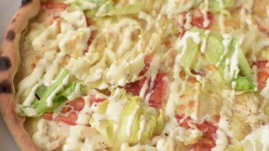 Peynirli ve tavuklu İtalyan sezar pizzası, marul yaprağı ve sos. Fast food, dilimlenmiş pizza.