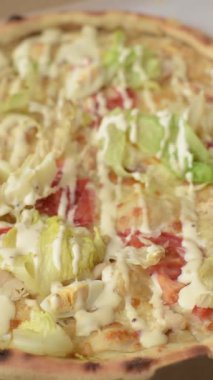 Peynirli ve tavuklu İtalyan sezar pizzası, marul yaprağı ve sos. Fast food, dilimlenmiş pizza.