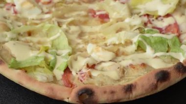 Peynirli ve tavuklu İtalyan sezar pizzası, marul yaprağı ve sos. Fast food, dilimlenmiş pizza.