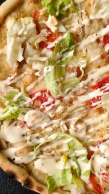 Peynirli ve tavuklu İtalyan sezar pizzası, marul yaprağı ve sos. Fast food, dilimlenmiş pizza.