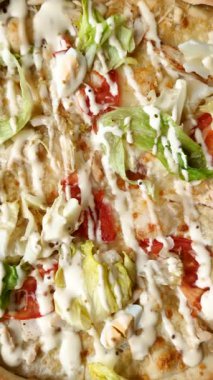 Peynirli ve tavuklu İtalyan sezar pizzası, marul yaprağı ve sos. Fast food, dilimlenmiş pizza.