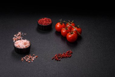 Koyu beton zeminde domates, tuz, baharat ve otlar pişirmek için gerekli malzemeler.