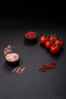 Koyu beton zeminde domates, tuz, baharat ve otlar pişirmek için gerekli malzemeler.
