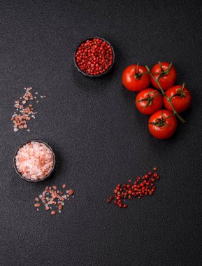 Koyu beton zeminde domates, tuz, baharat ve otlar pişirmek için gerekli malzemeler.