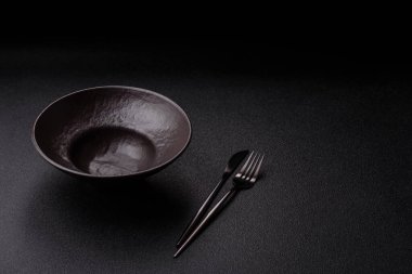 Yemek, risotto ya da makarna için boş yuvarlak siyah tabak yemek masasında mutfak gereçleri. Koyu arkaplanda boş tabak