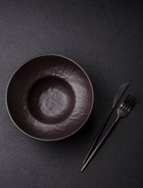 Yemek, risotto ya da makarna için boş yuvarlak siyah tabak yemek masasında mutfak gereçleri. Koyu arkaplanda boş tabak