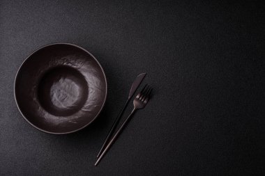 Yemek, risotto ya da makarna için boş yuvarlak siyah tabak yemek masasında mutfak gereçleri. Koyu arkaplanda boş tabak