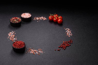 Koyu beton zeminde domates, tuz, baharat ve otlar pişirmek için gerekli malzemeler.